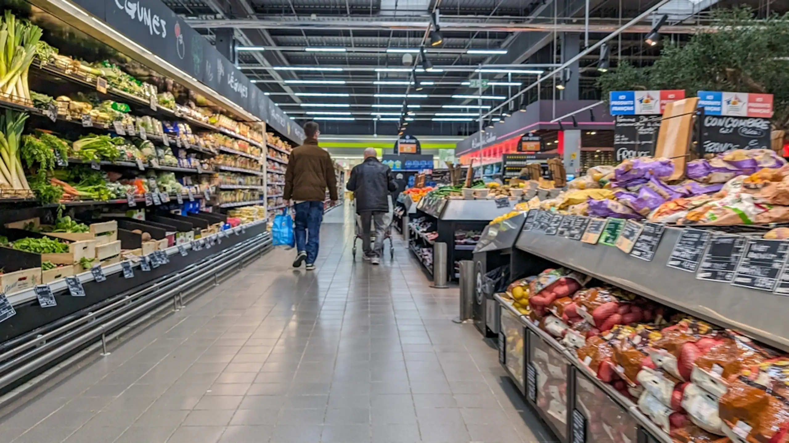 Deux personnes de dos dans l'allée d'un supermarché.