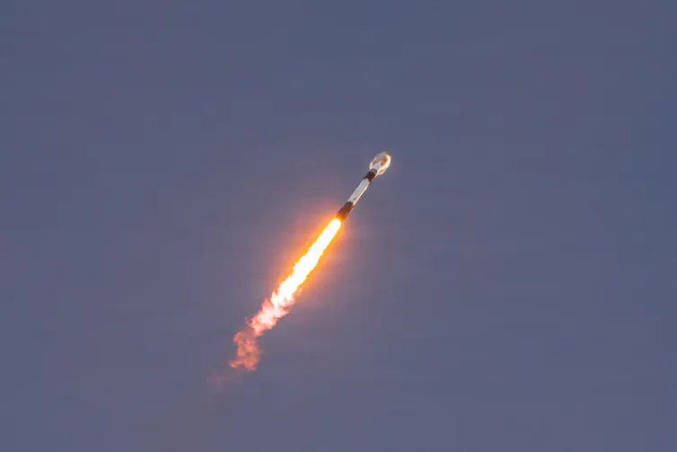 A rocket, moving upwards propelled by a plume of flame