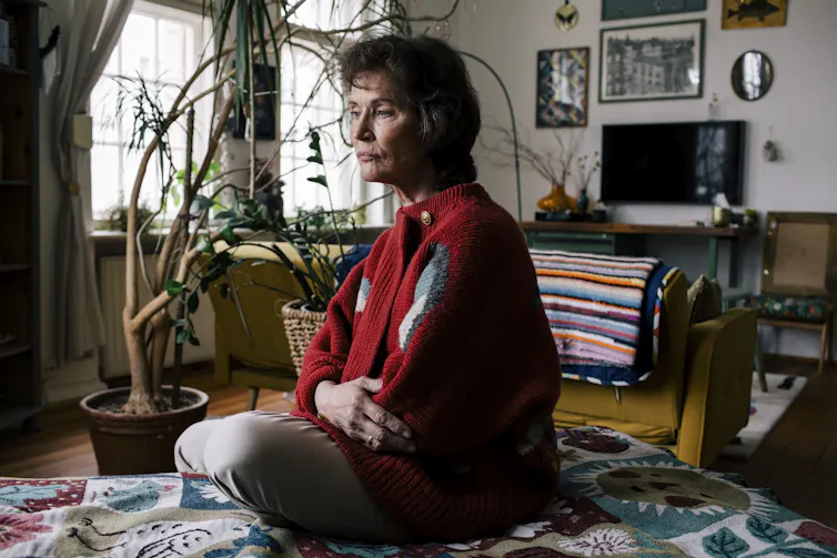 A woman sits in her loungeroom, deep in thought