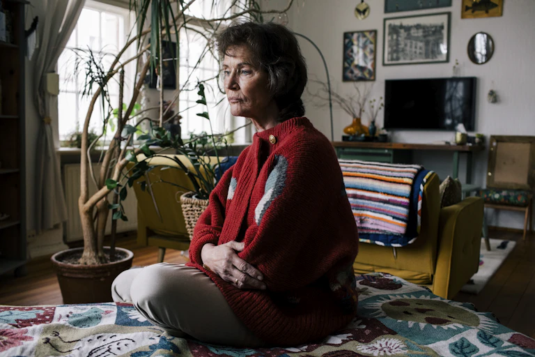 A woman sits in her loungeroom, deep in thought