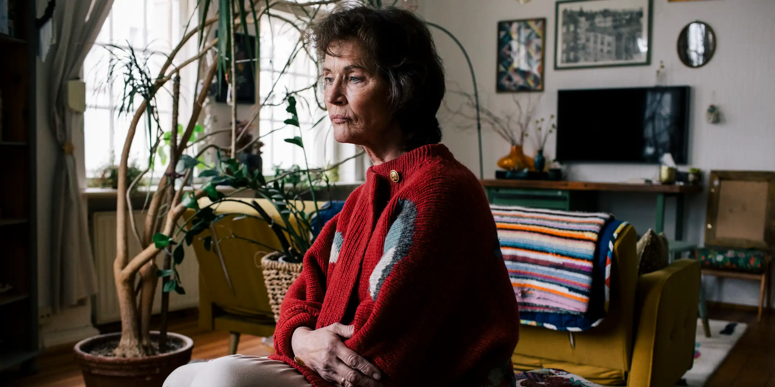 A woman sits in her loungeroom, deep in thought