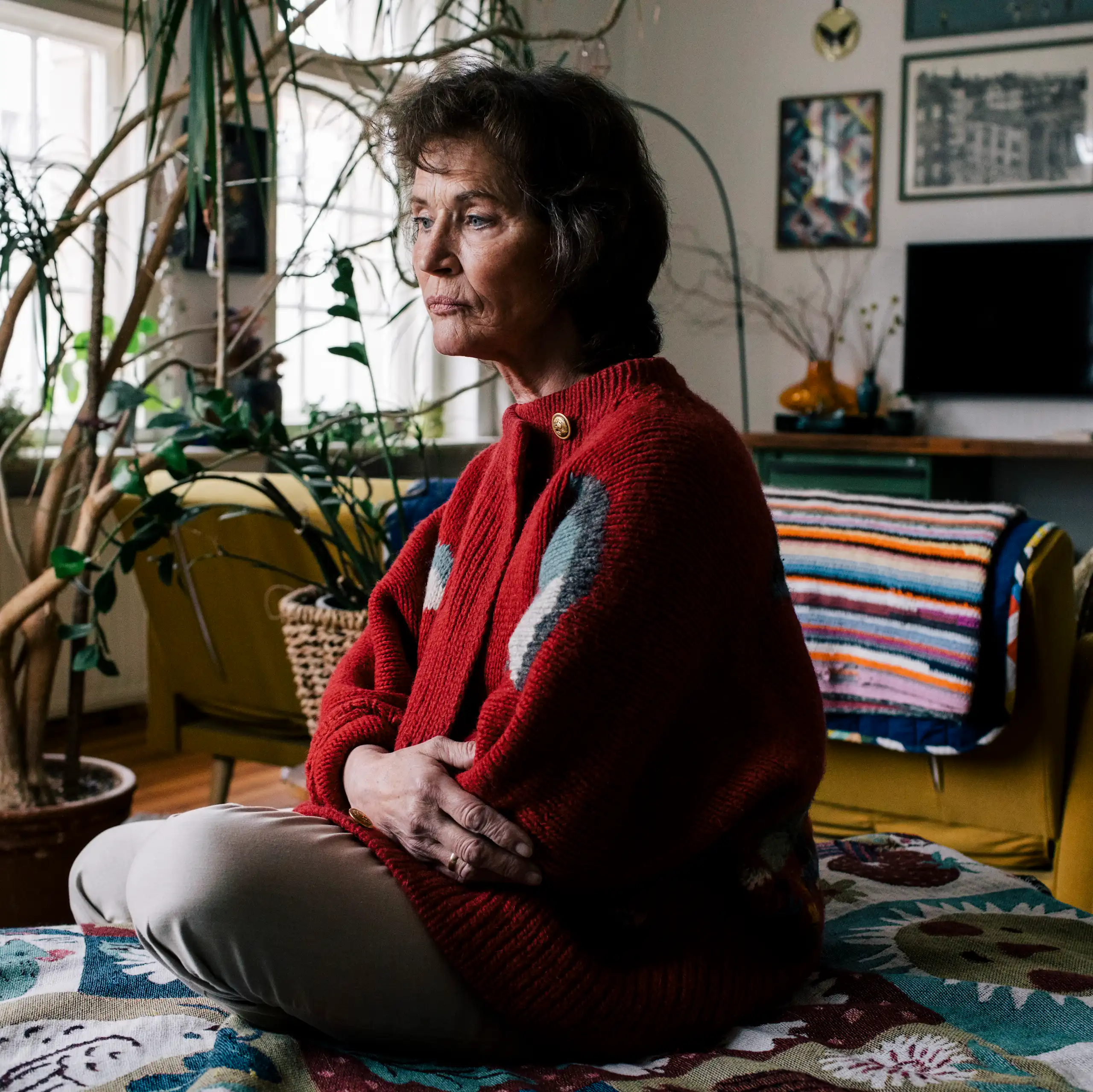 A woman sits in her loungeroom, deep in thought