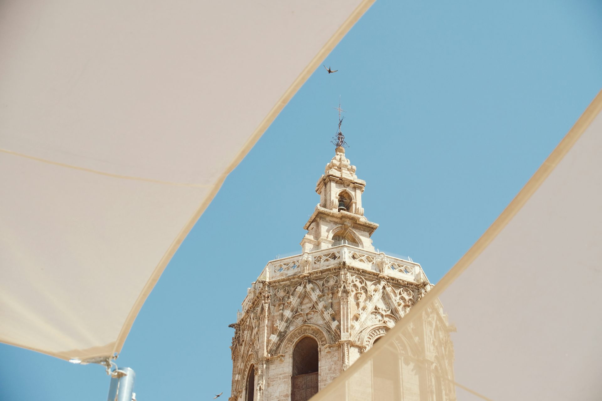 Entre dos tendals a una plaça es deixa veure la part de dalt de la torre del Micalet.