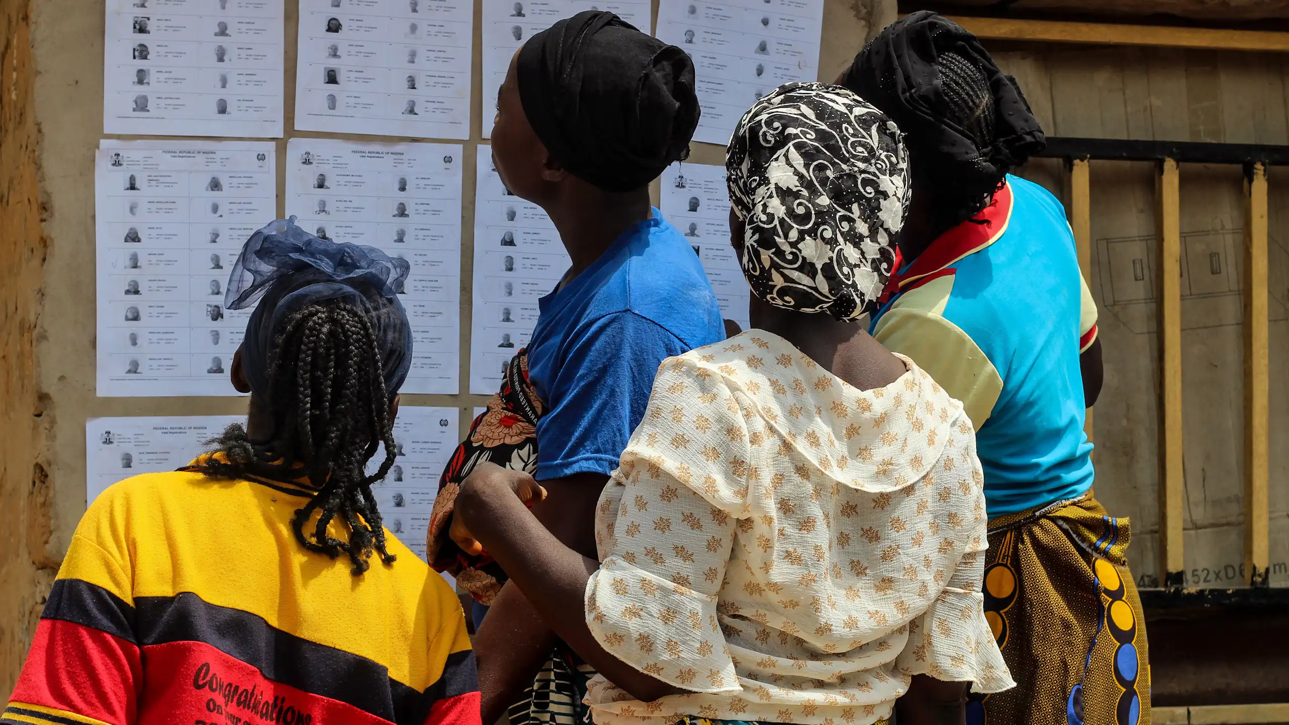 Four women checking names displayed at a voting centre