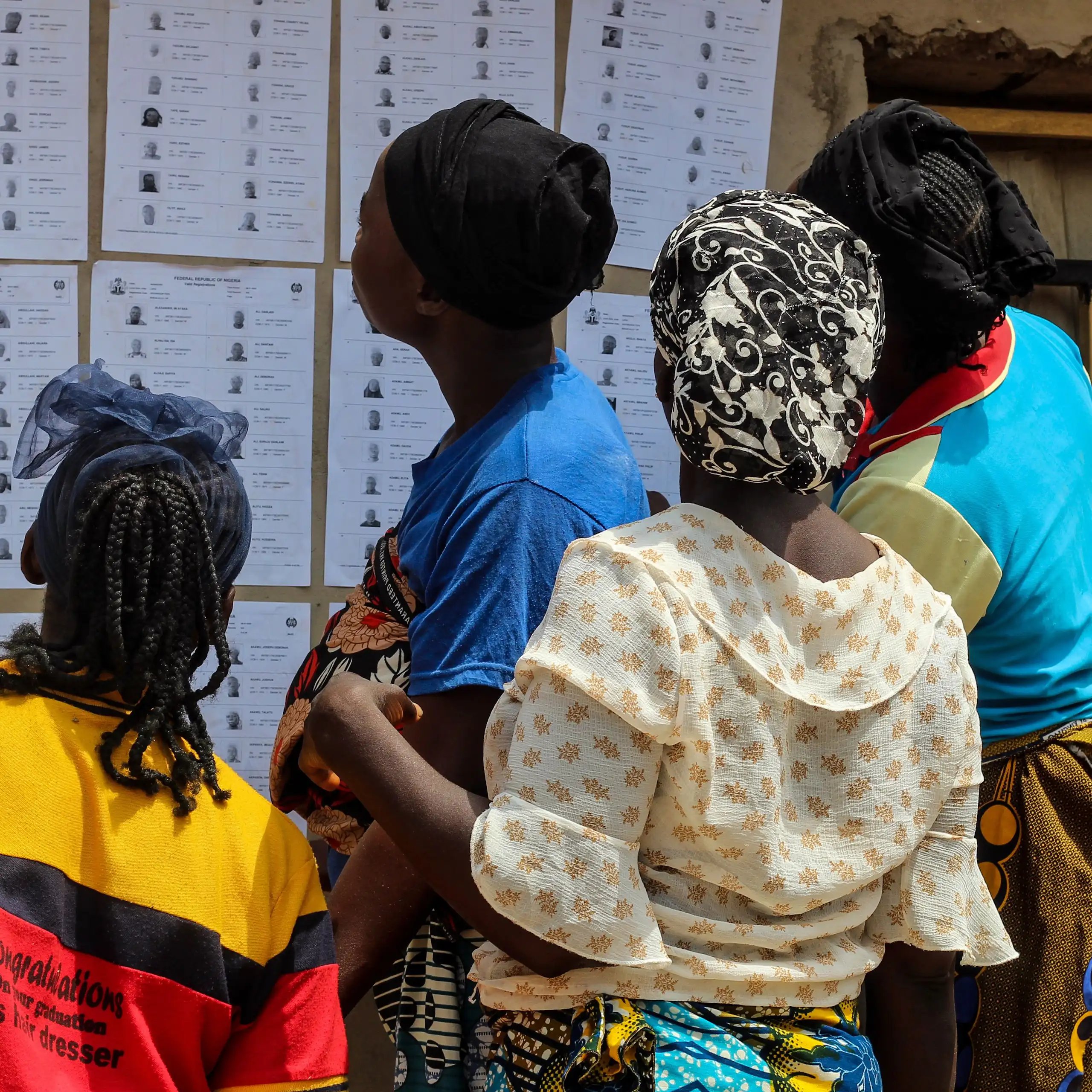 Four women checking names displayed at a voting centre