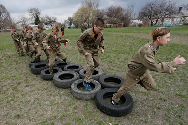 Ukrainan boys run through tires as part of a military game.