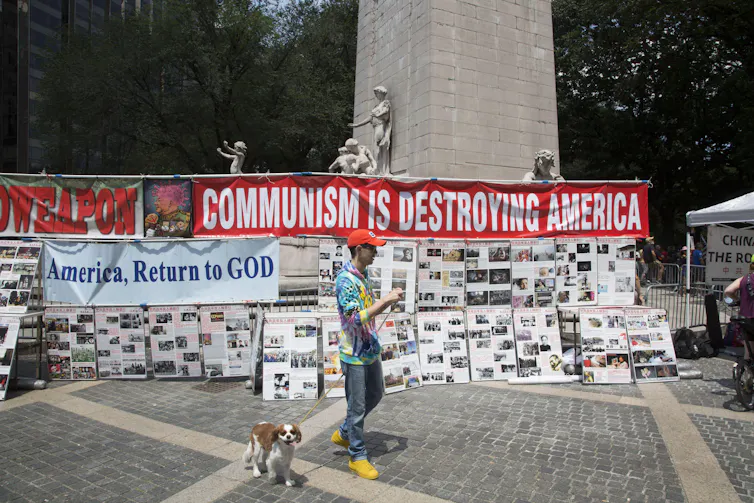 A man and his dog walk past a display of anti-communist propaganda.