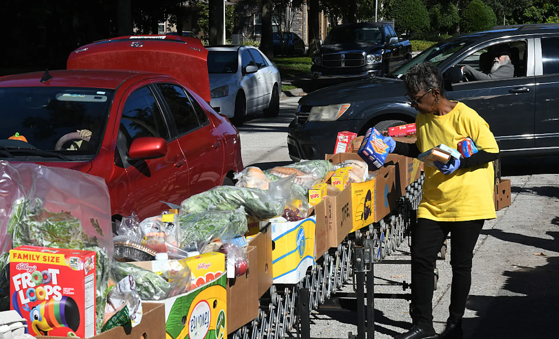 A woman in a yellow shirt packs food into boxes.