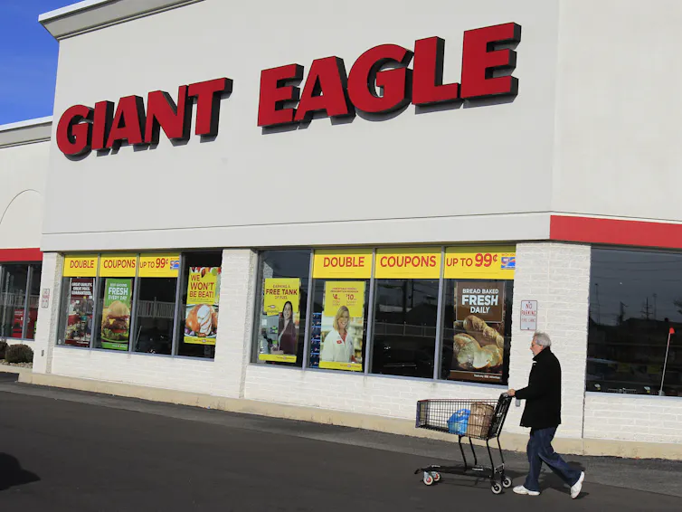 A man pushes a grocery cart outside a Giant Eagle grocery store.