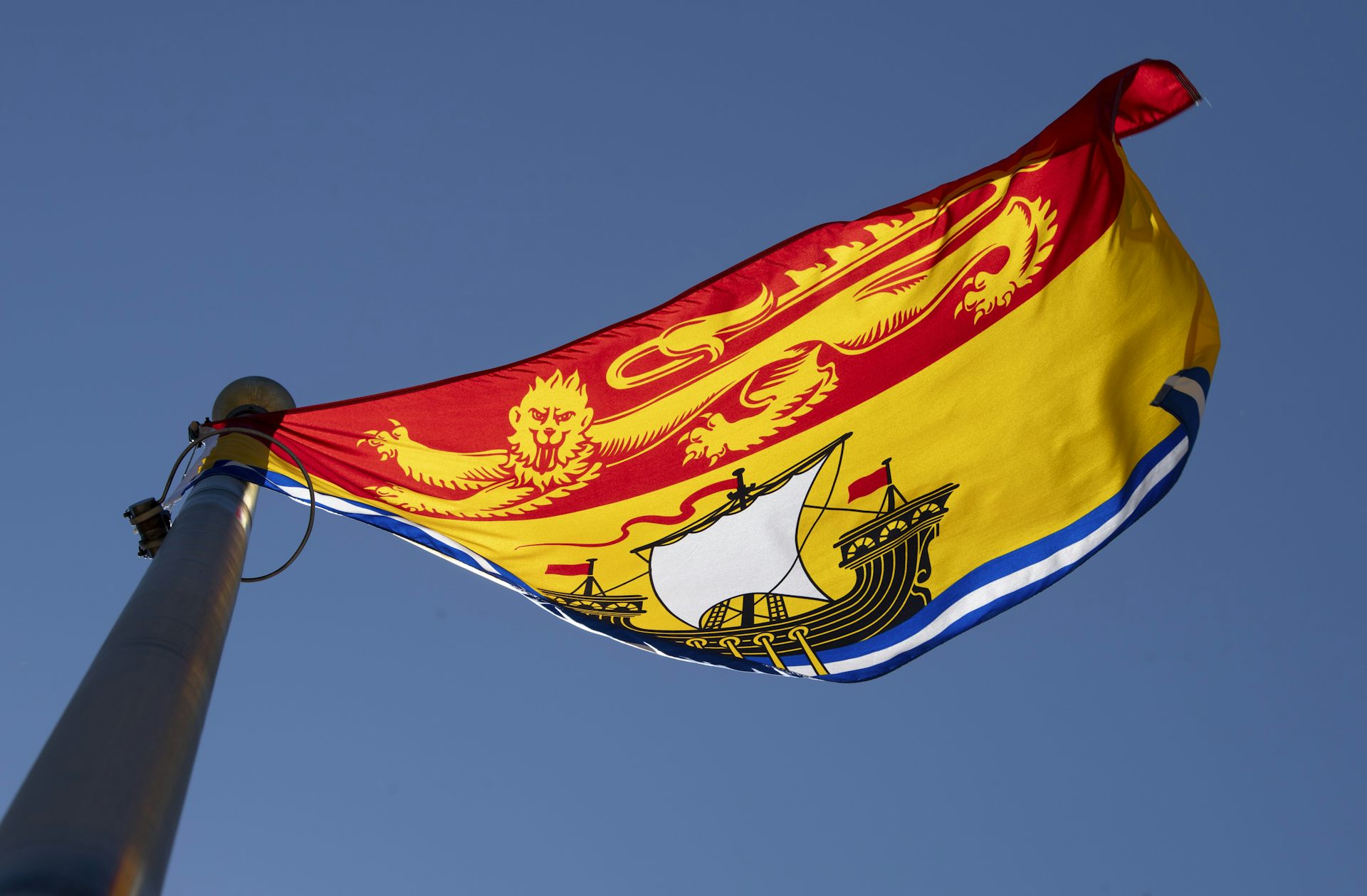 Le drapeau provincial du Nouveau-Brunswick, rouge et jaune, hissé sur un mât.