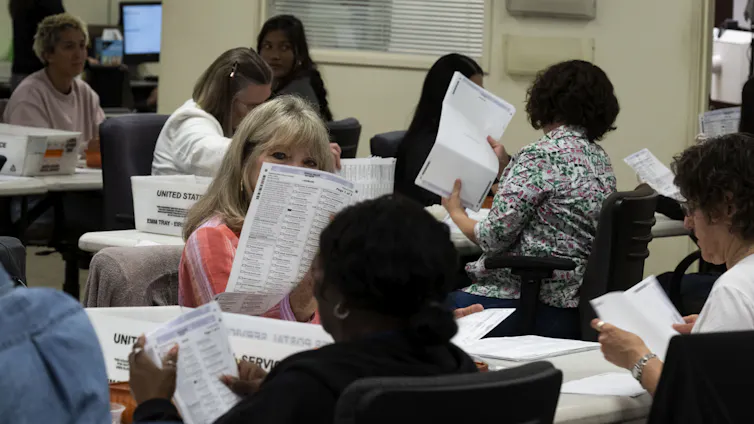 A group of people sitting at tables looking at pieces of paper.
