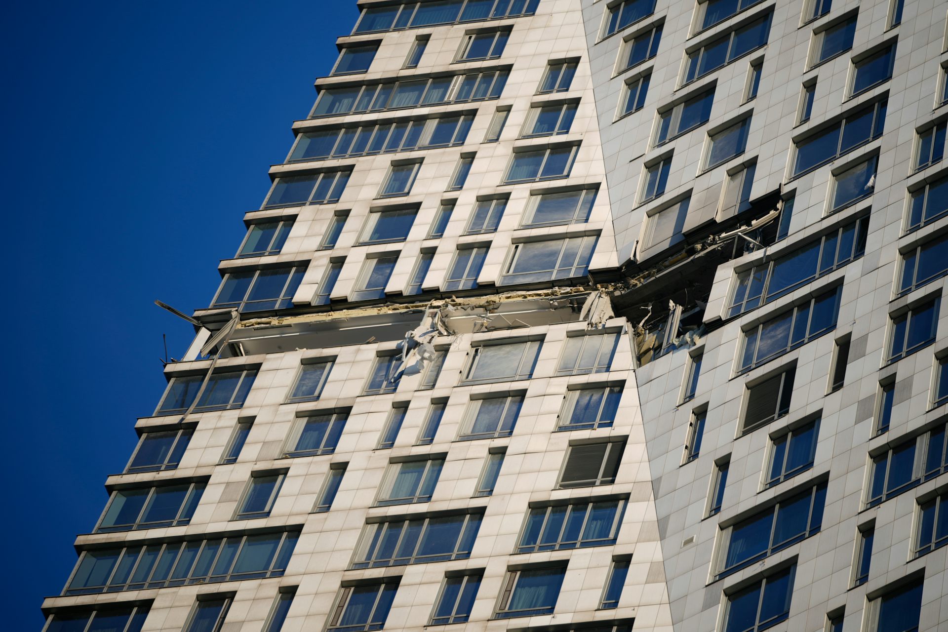 Debris dangles from an highrise apartment building.