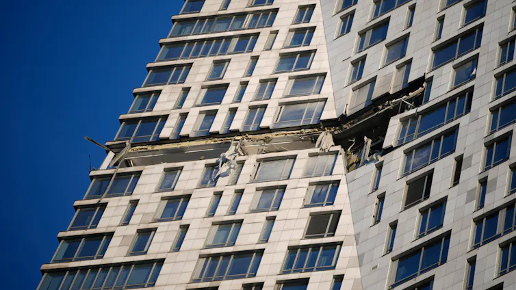 Debris dangles from an highrise apartment building.