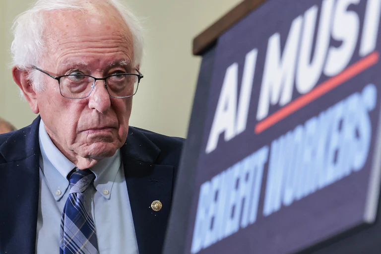 Bernie Sanders is flanked by a sign saying 'AI must benefit workers.'