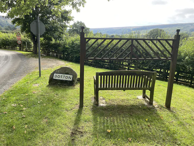 Bench at entrance to picturesque village.