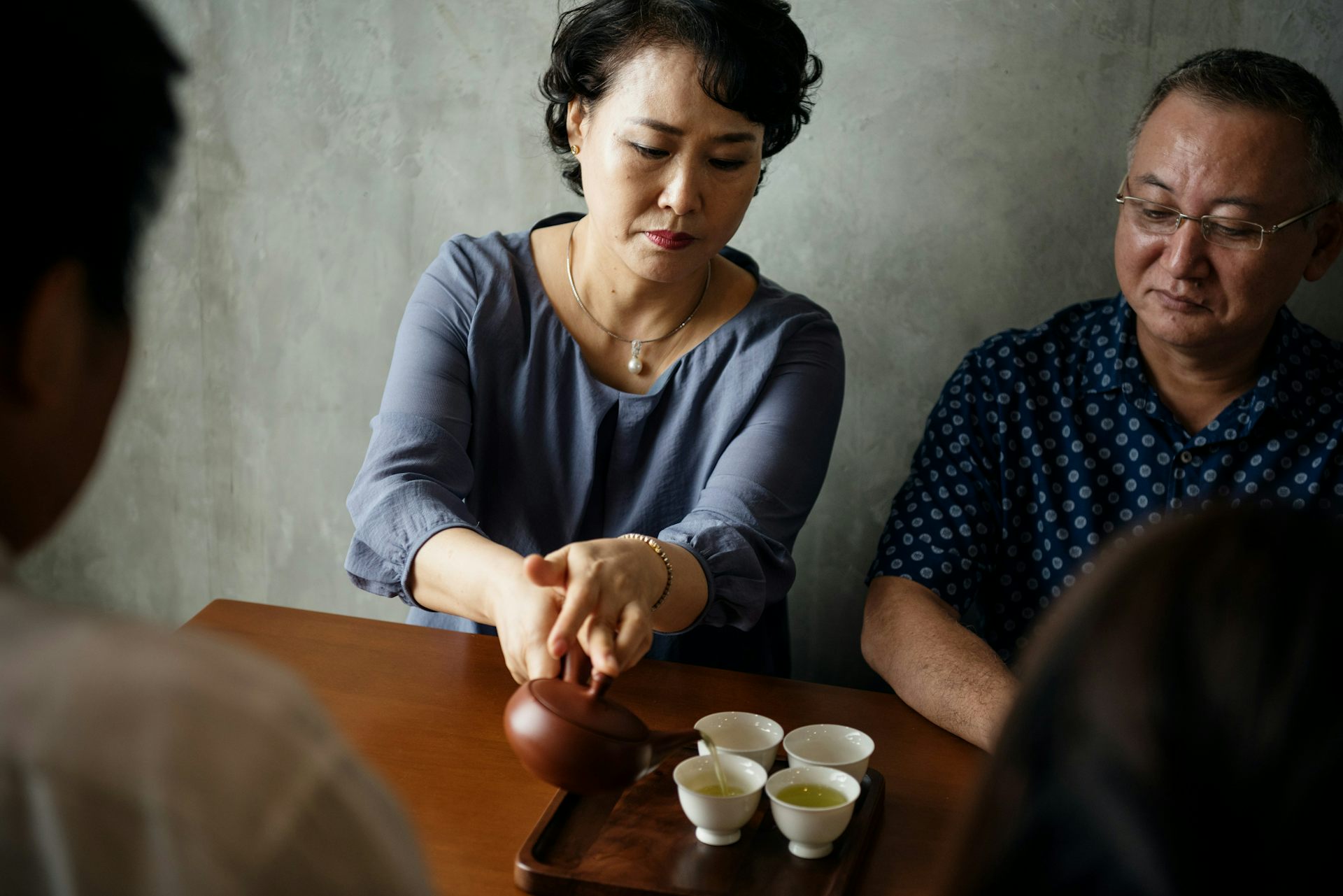 Four Asian men and women sitting at a table drinking tea.
