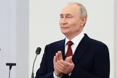 Los ataques con drones en Ucrania tienen impacto en Rusia, pero los líderes rusos siguen comprometidos con la guerra 2 Un hombre calvo con expresión engreída aplaude.