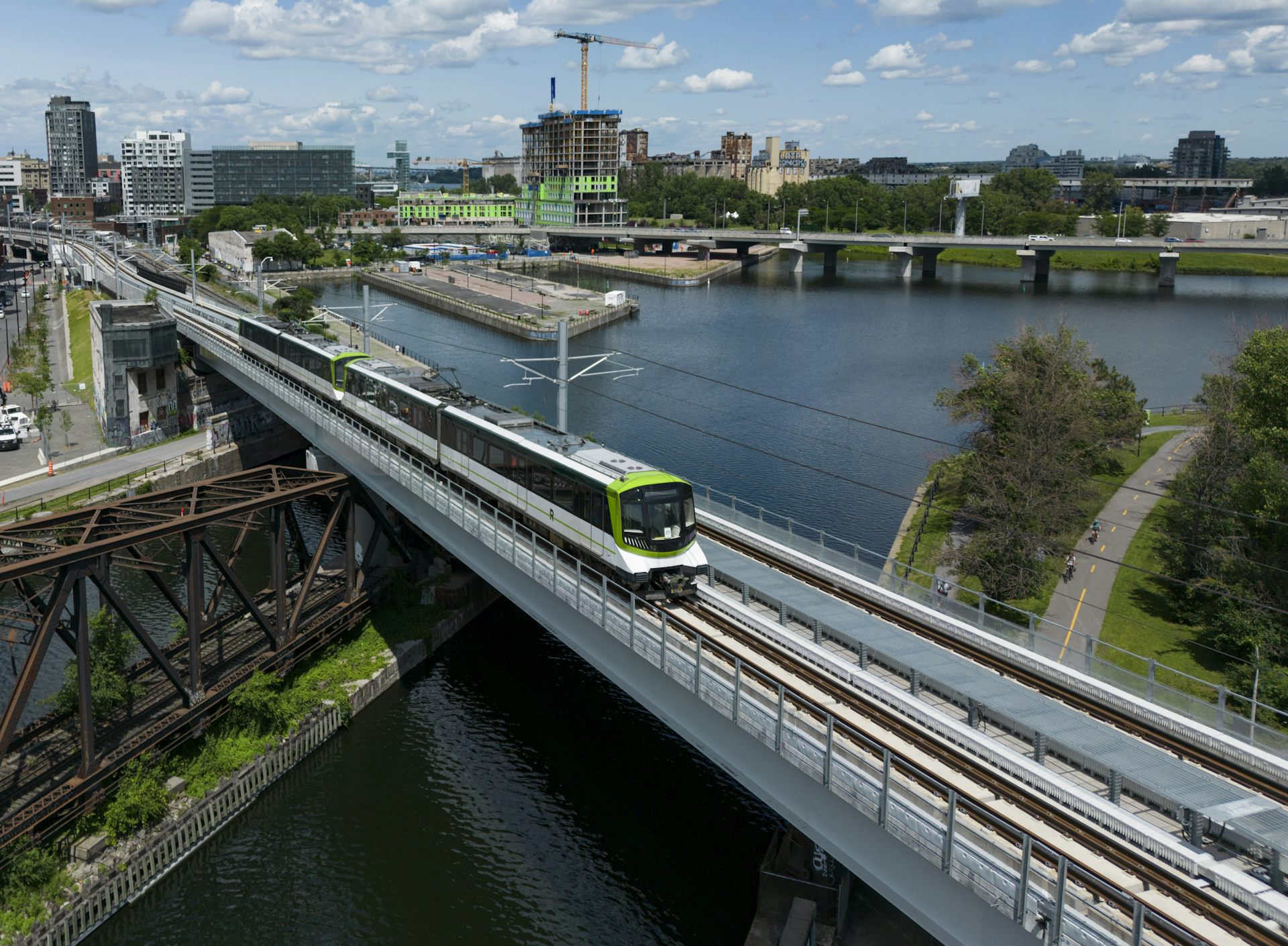 Le REM de Montréal circule sur ses rails tandis qu'on voit la ville en arrière-plan
