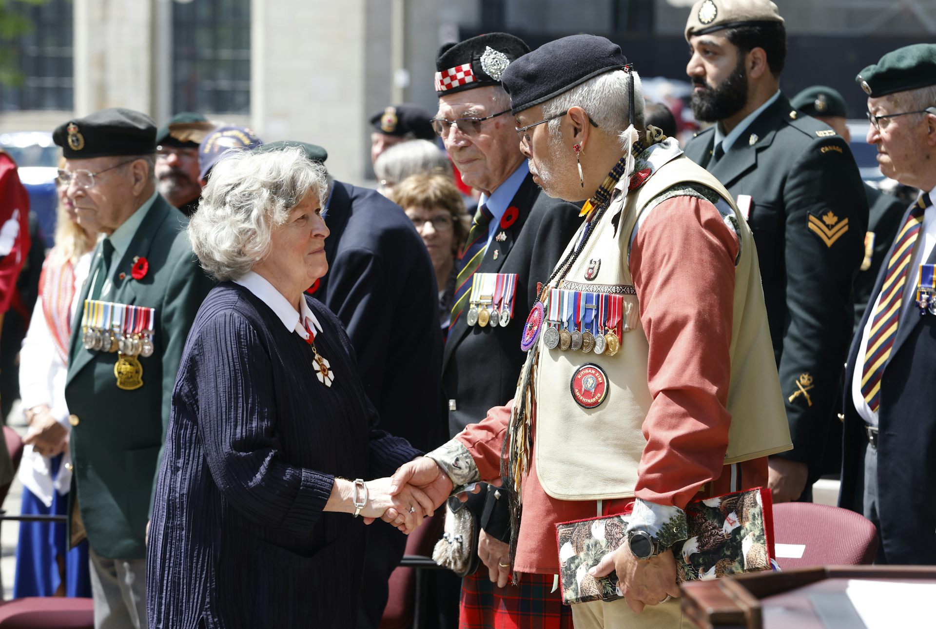 La gouverneure générale Louise Arbour serre la main d’un vétéran autochtone, qui porte de nombreuses décorations militaires
