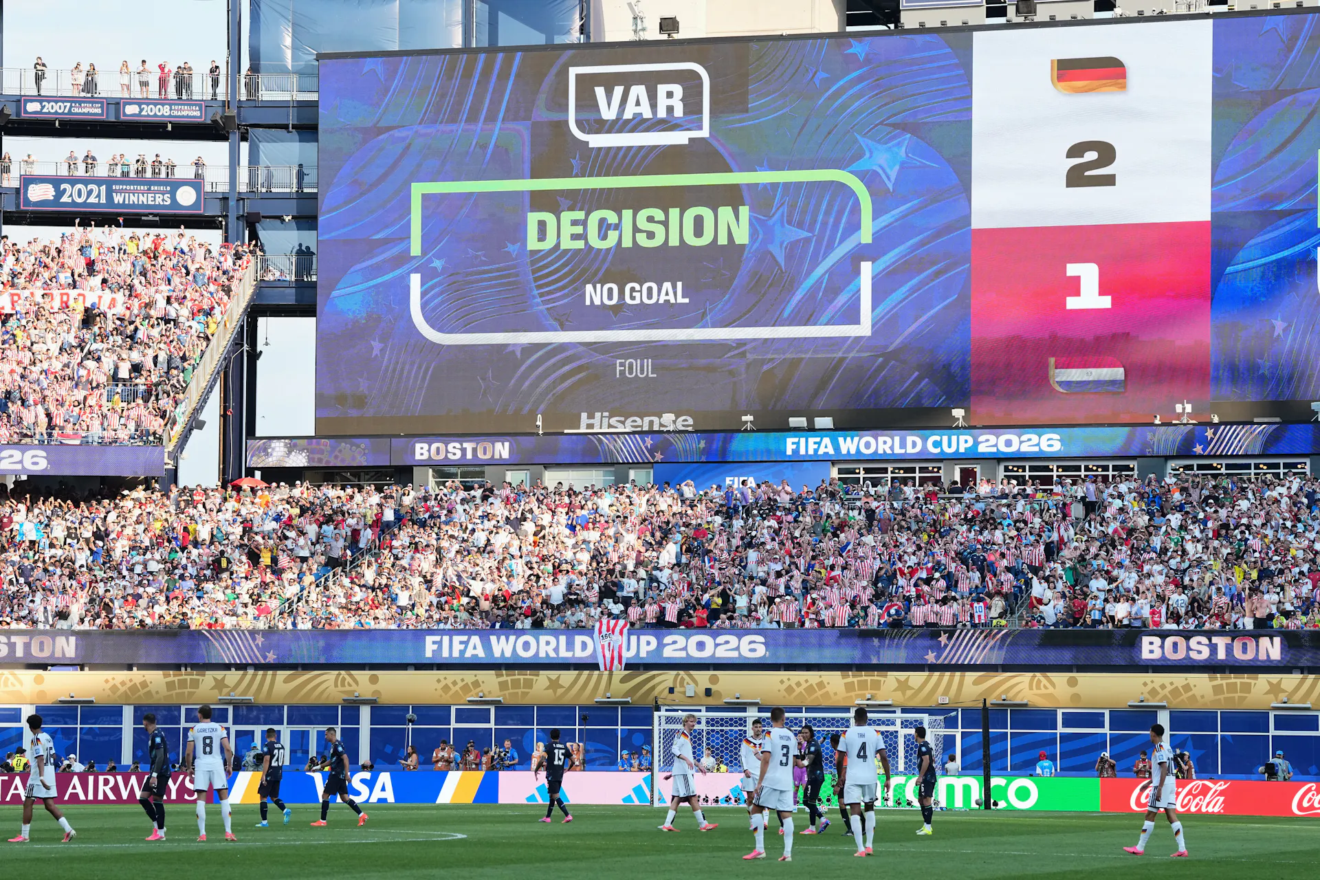 a large video display board in a crowded stadium