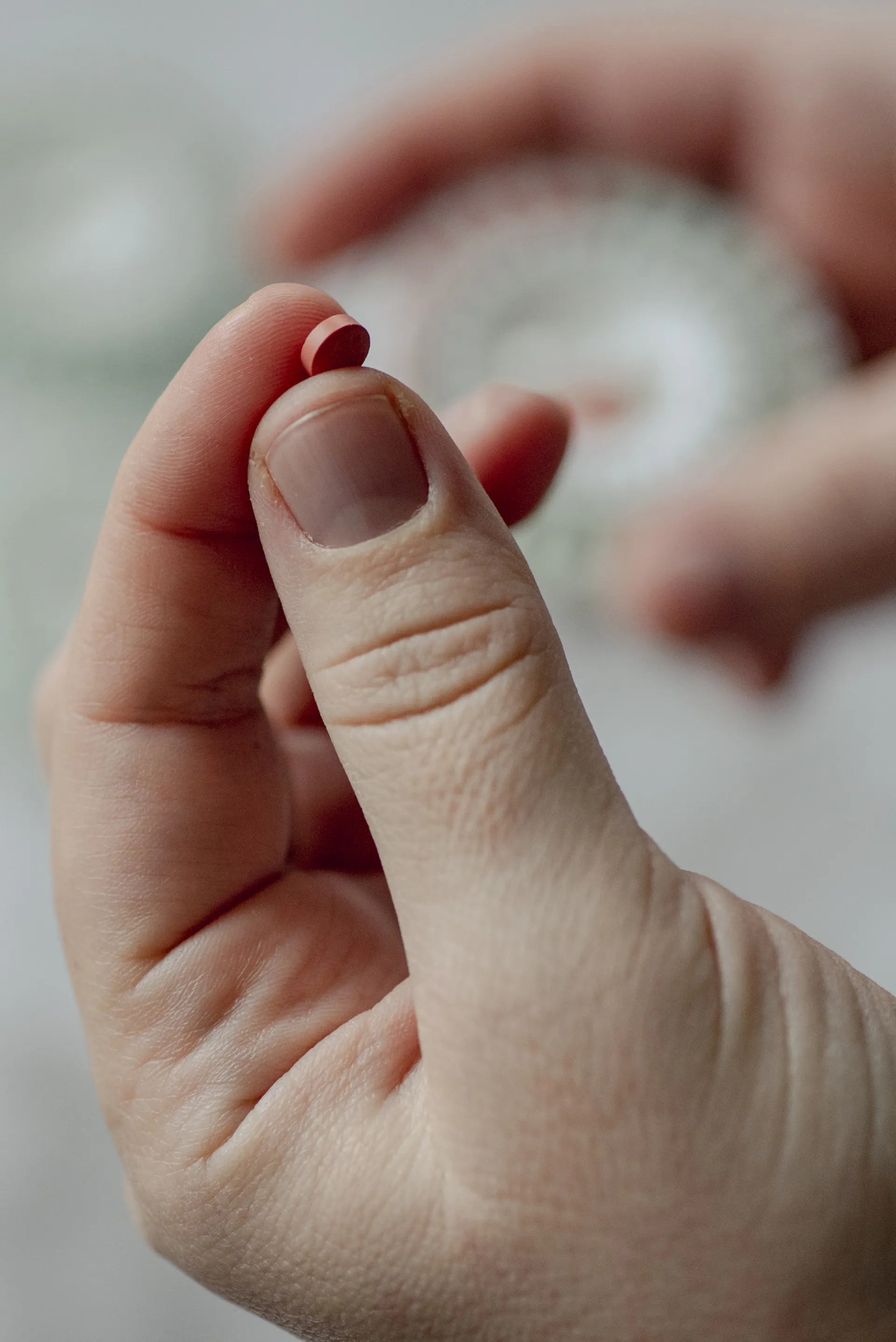 Close-up of hand holding a small round pill