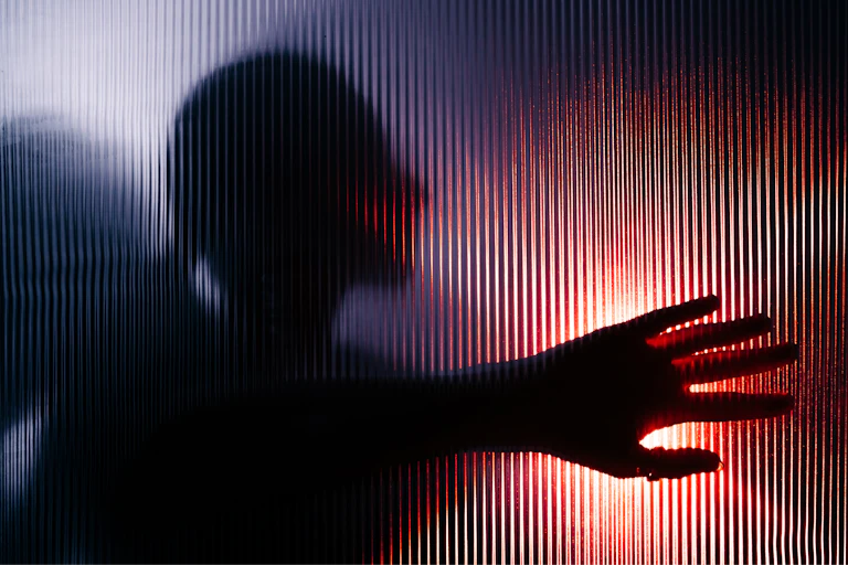 Blurred figure with raised hand seen through opaque glass