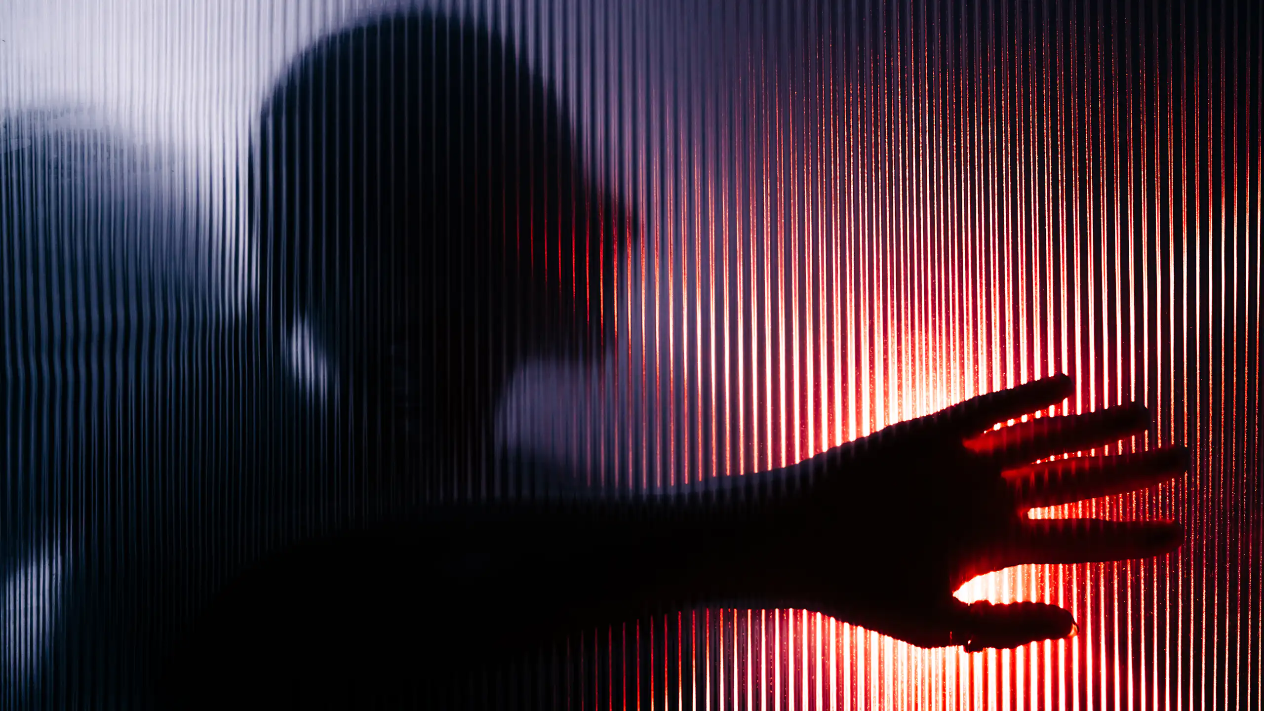 Blurred figure with raised hand seen through opaque glass