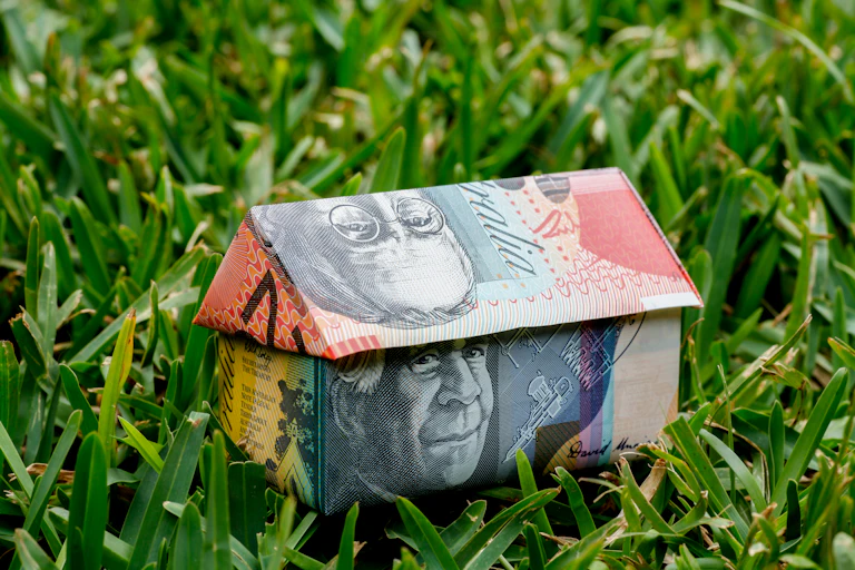 An origami house made with Australian money, sitting on a grass lawn