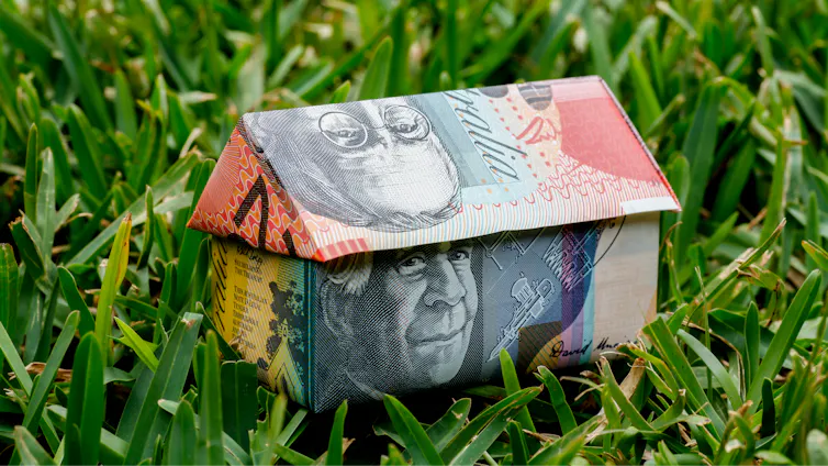 An origami house made with Australian money, sitting on a grass lawn