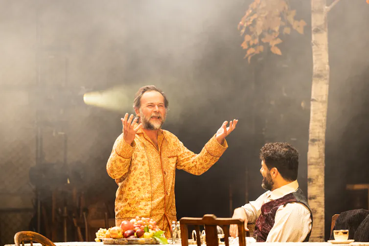 Production image: as Vanya speaks, you can see stage lighting behind him.