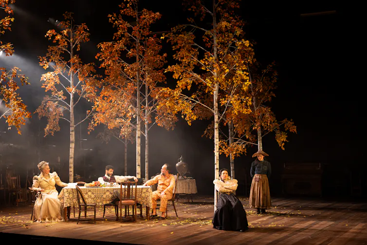 Production image: the cast slump in chairs.