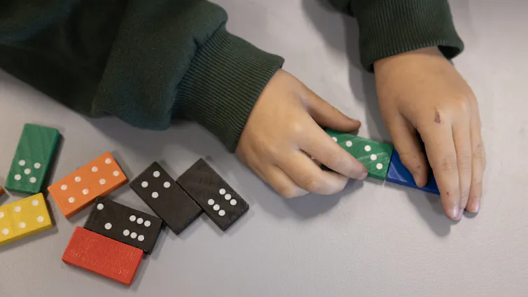 A child's hands playing with colourful dominos