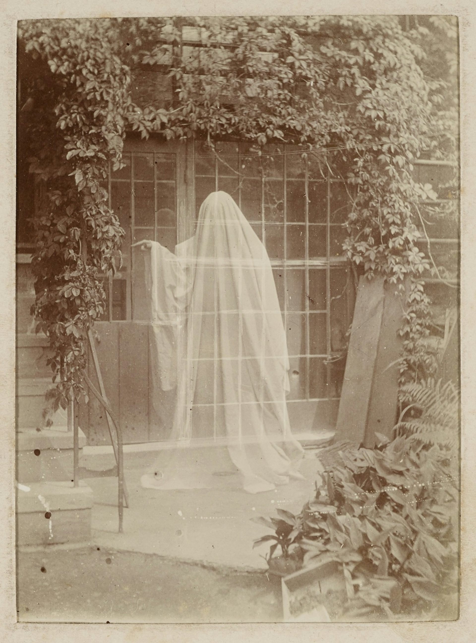 A sepia photograph showing a classic ghost-in-a-sheet figure