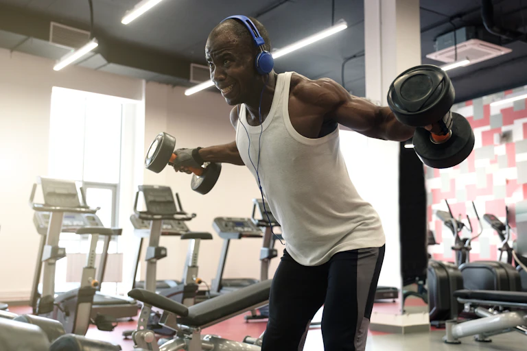 Man doing exercises with dumbbells for back at gym