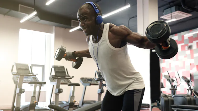 Man doing exercises with dumbbells for back at gym
