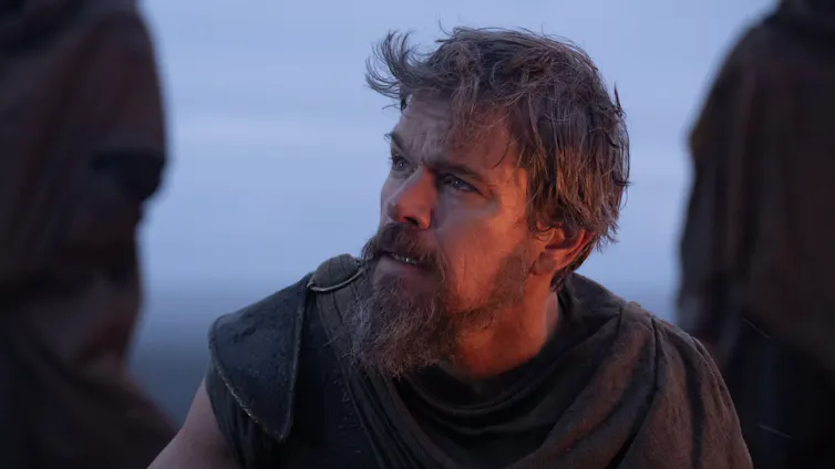 An exhausted middle-aged man with a thick beard gazes forlornly into the distance.