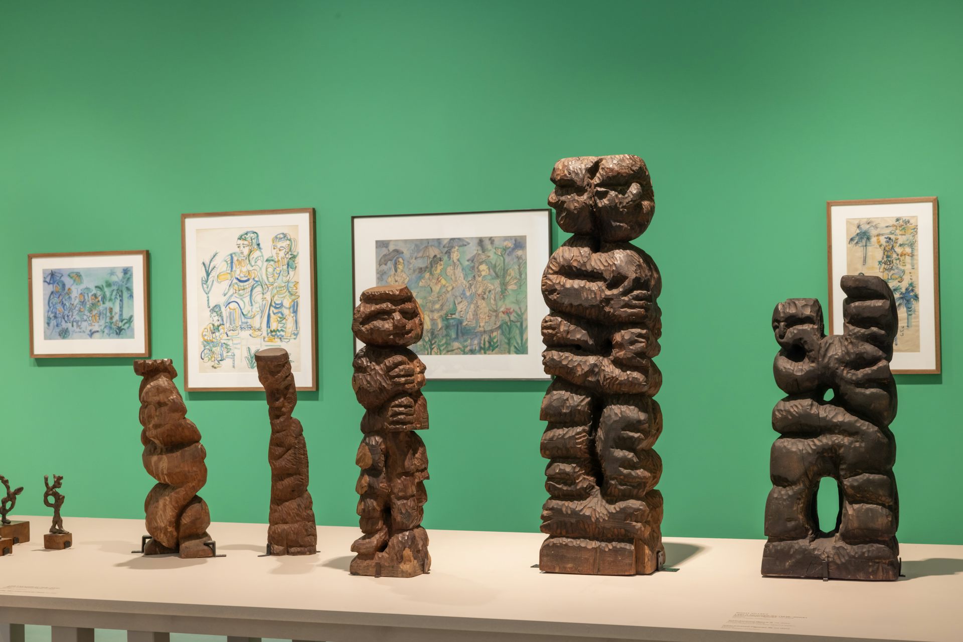 Sculptures on display in front of a green wall