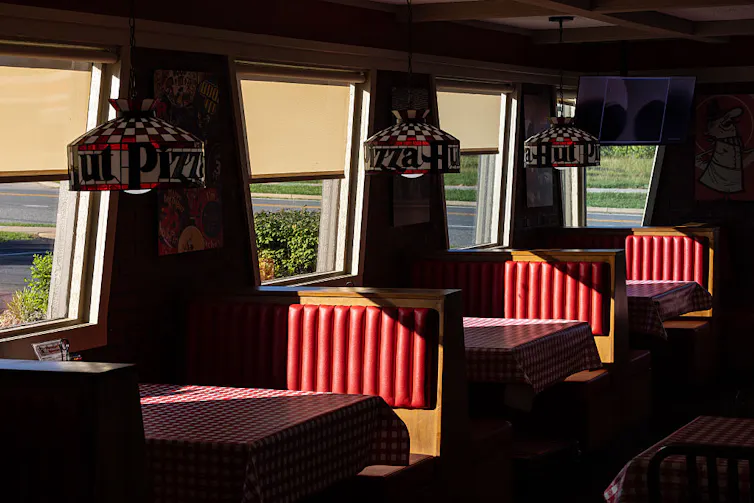 The interior of a Pizza Hut restaurant with sunlight coming in through the windows.