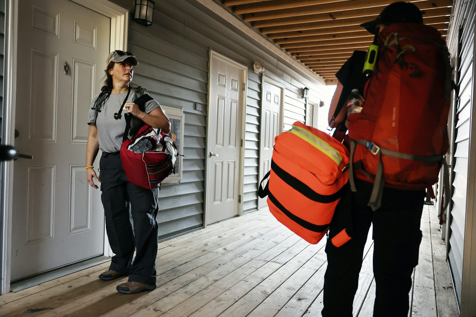 Two people with medical bags stand in a hallway to doors.