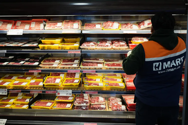 An employee stands in front of the meat department in a grocery store in Schaumburg, Ill.