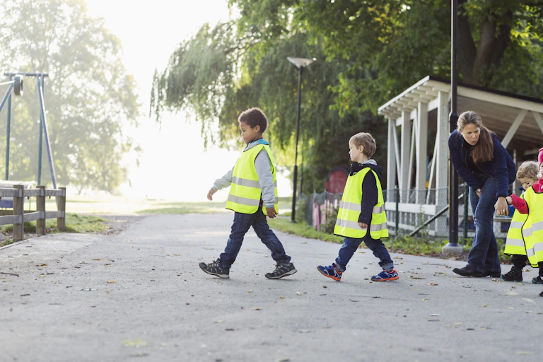 Children in safety vests walk to a playground.