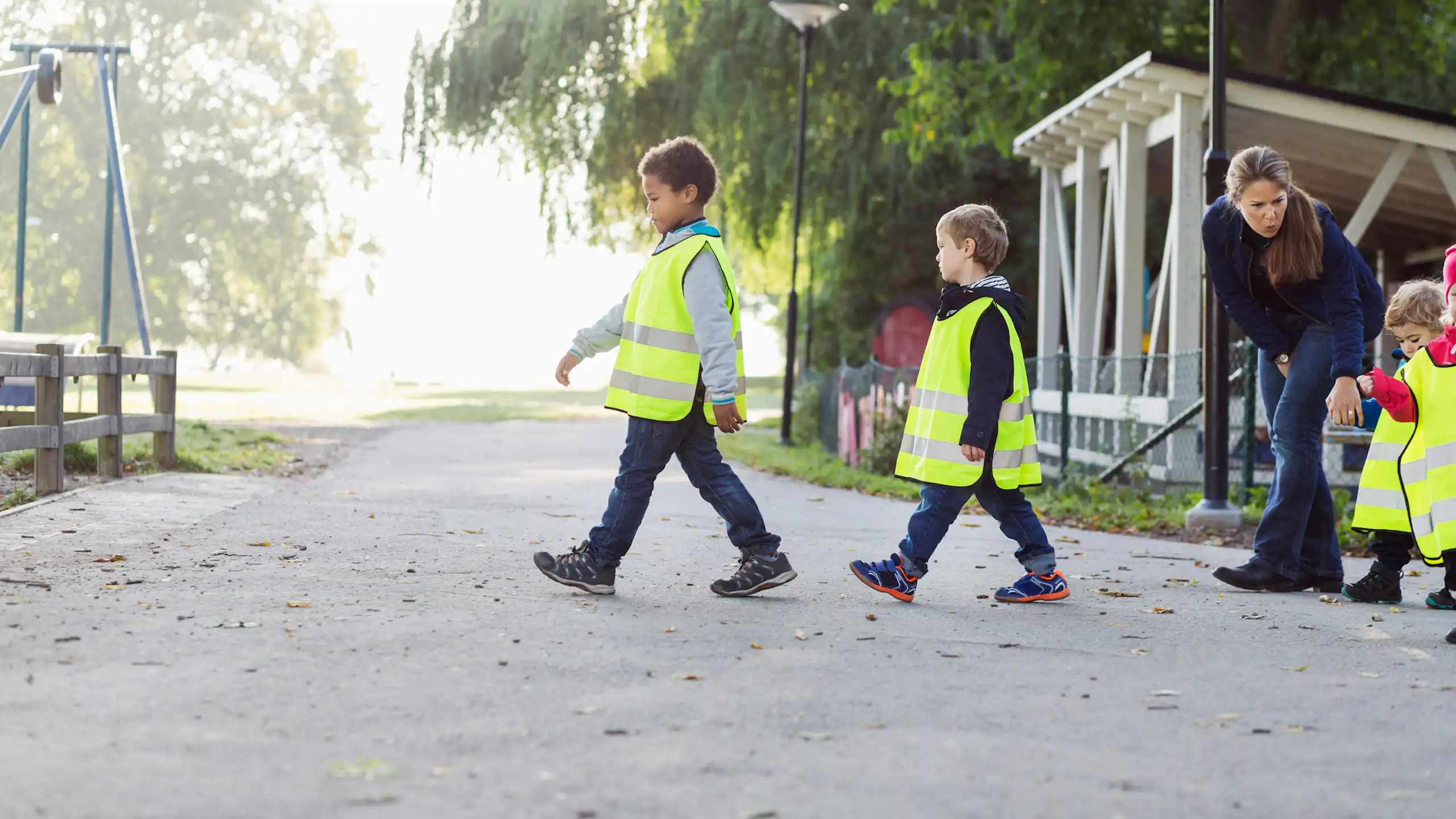 Children in safety vests walk to a playground.