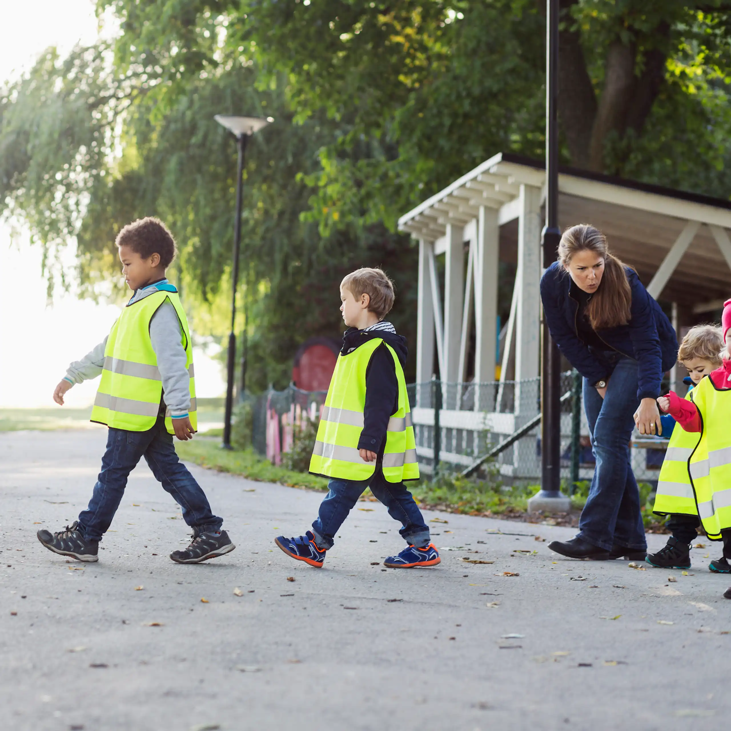 Children in safety vests walk to a playground.