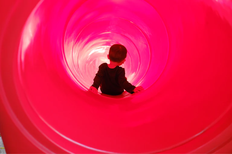 Toddler boy riding a tube slide.