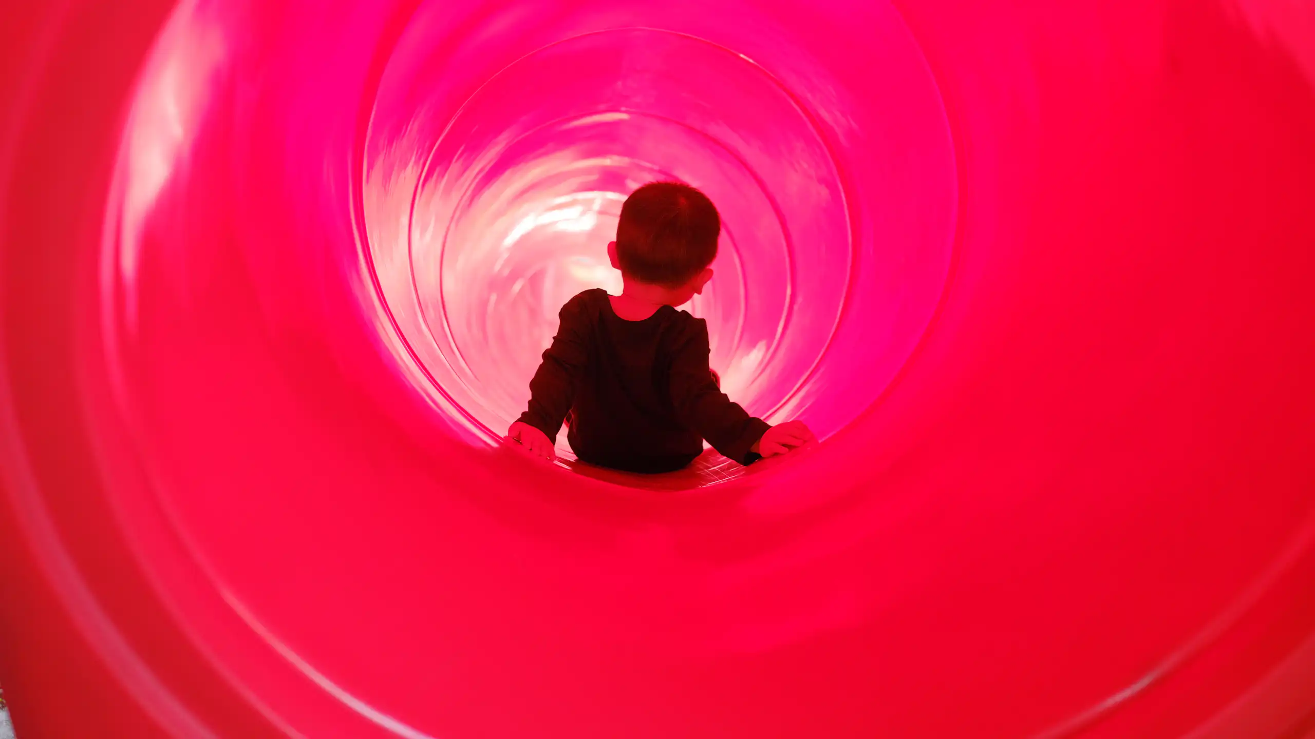 Toddler boy riding a tube slide.