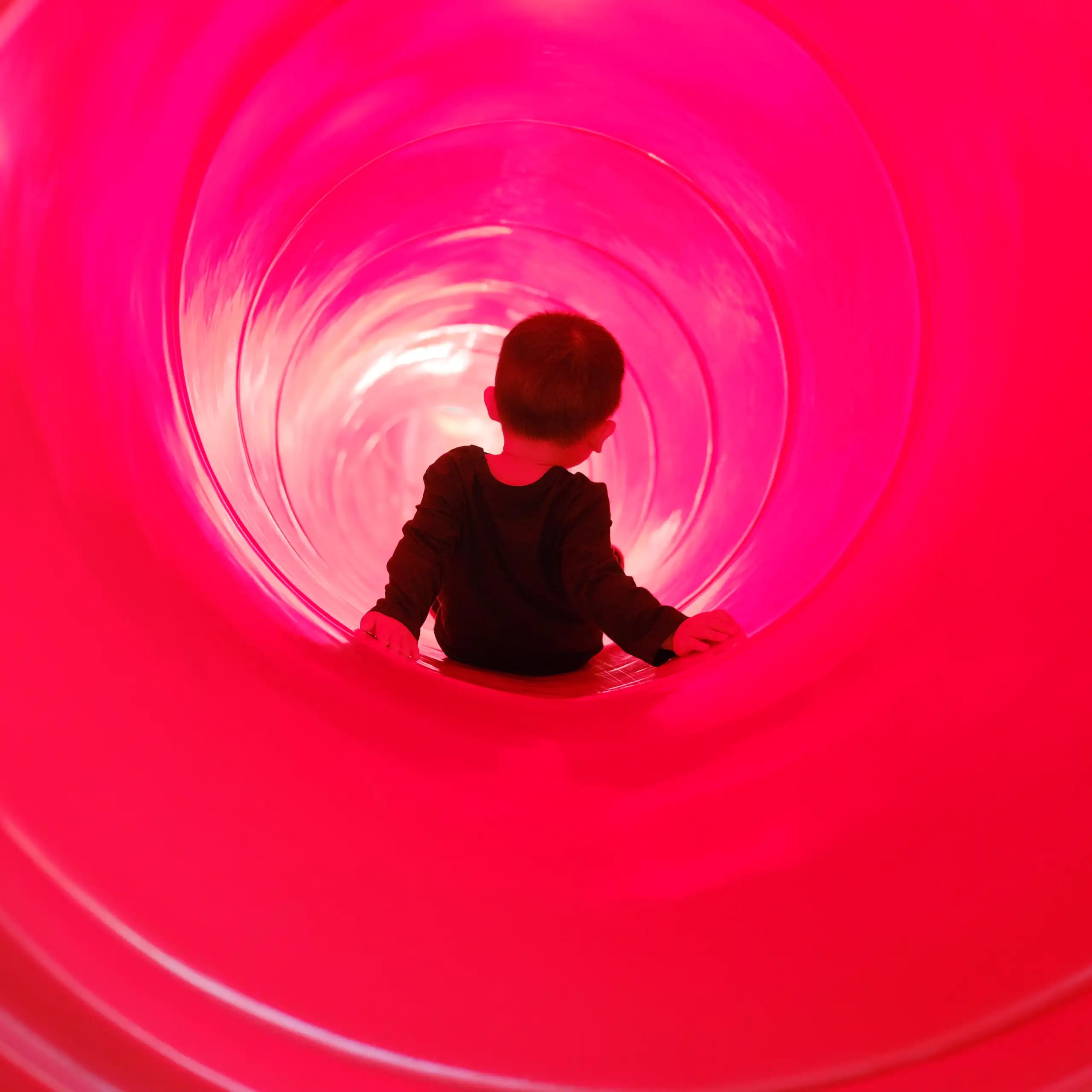 Toddler boy riding a tube slide.