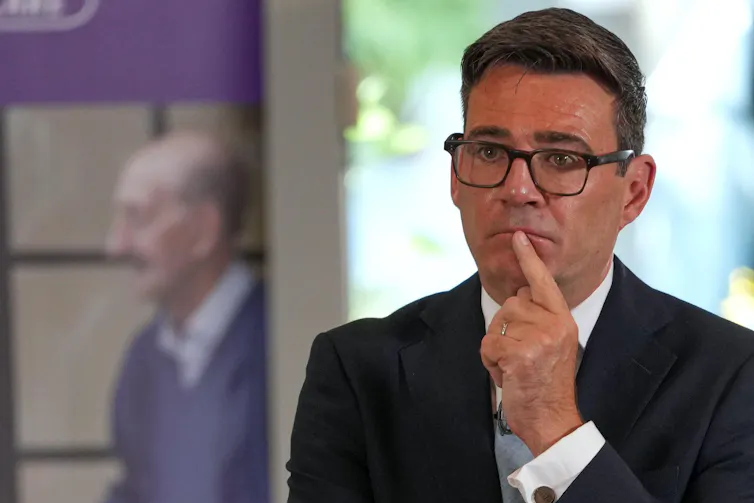 Andy Burnham holds his index finger to his lip looking concerned.