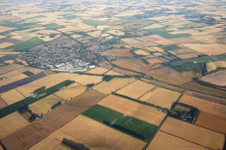 aerial shot with town and yellow dry fields of crops