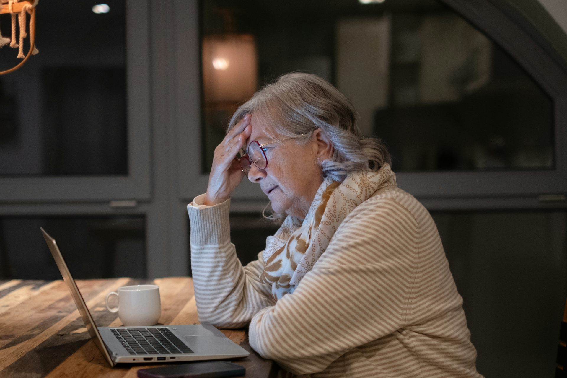 Una dona gran davant d'un ordinador portàtil en un ambient casolà.