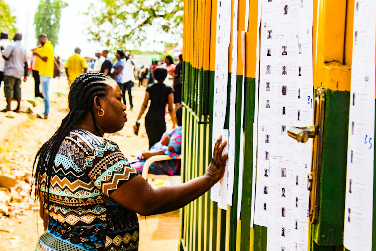 A woman looking at a list of names pasted on a multicoloured wall